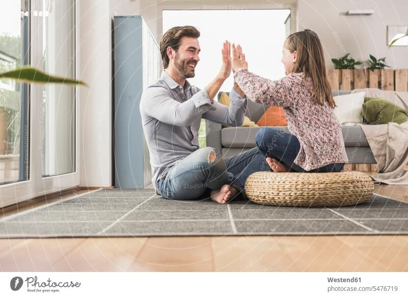 Young man and little girl sitting at home, giving high five optimistic optimism High Five high fiving Hi-Five high-fiving High-Five sitting on ground