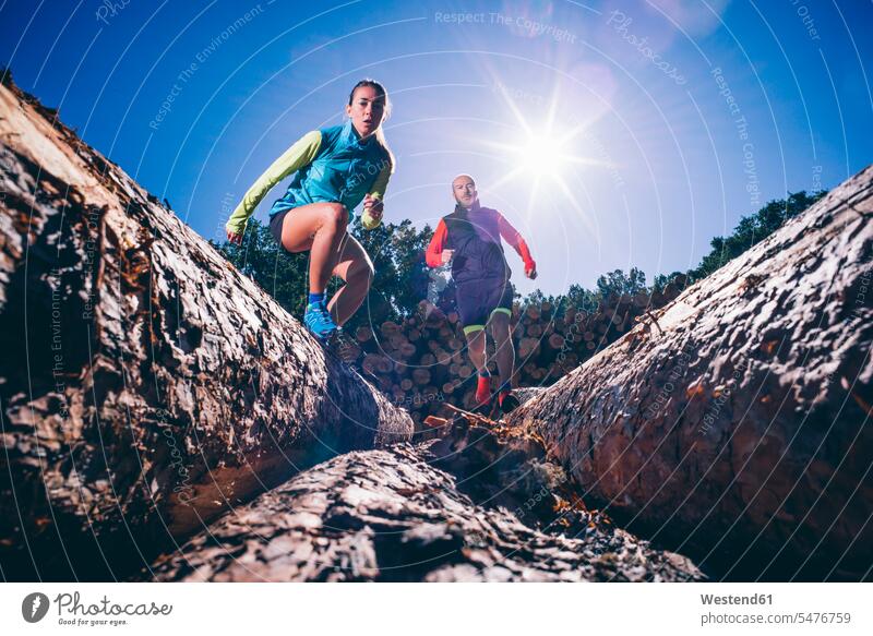 Mature couple running on logs against clear blue sky during sunny day color image colour image Spain outdoors location shots outdoor shot outdoor shots