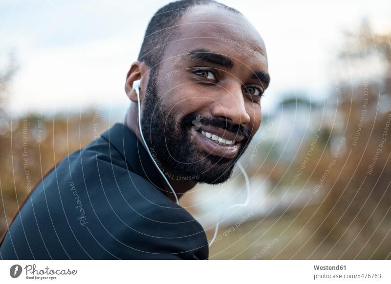 Portrait of smiling young businessman with earphones outdoors human human being human beings humans person persons African black black ethnicity coloured 1