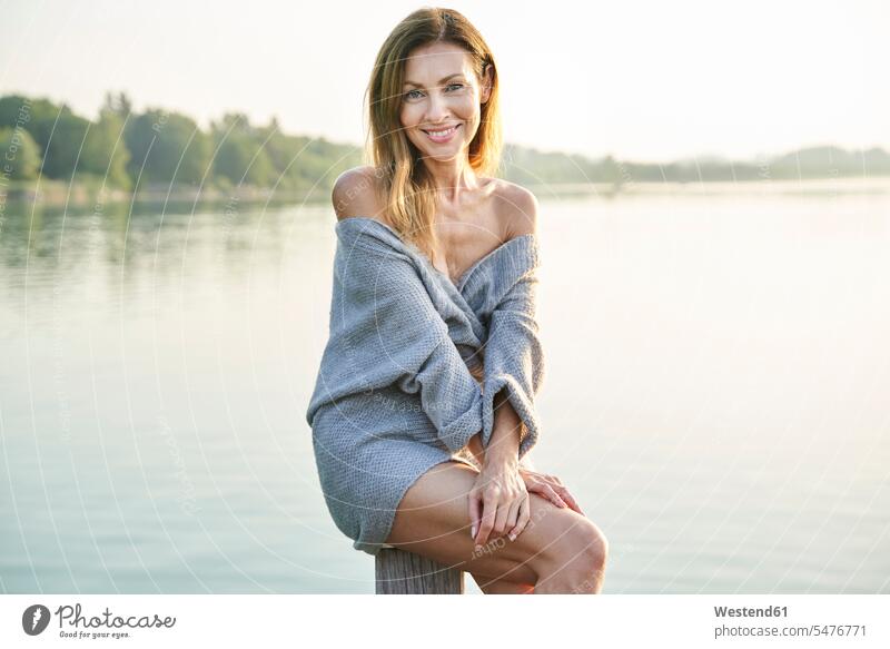 Portrait of mature woman sitting on pole at a lake human human being human beings humans person persons caucasian appearance caucasian ethnicity european 1