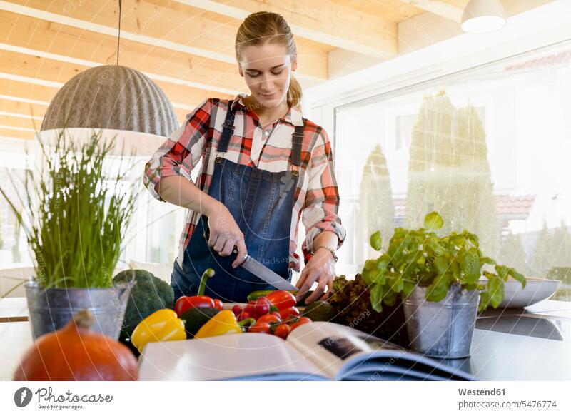 Pregnant woman in kitchen at home cutting cucumber females women pregnant Pregnant Woman Cucumber cucumis sativus Cucumbers Adults grown-ups grownups adult