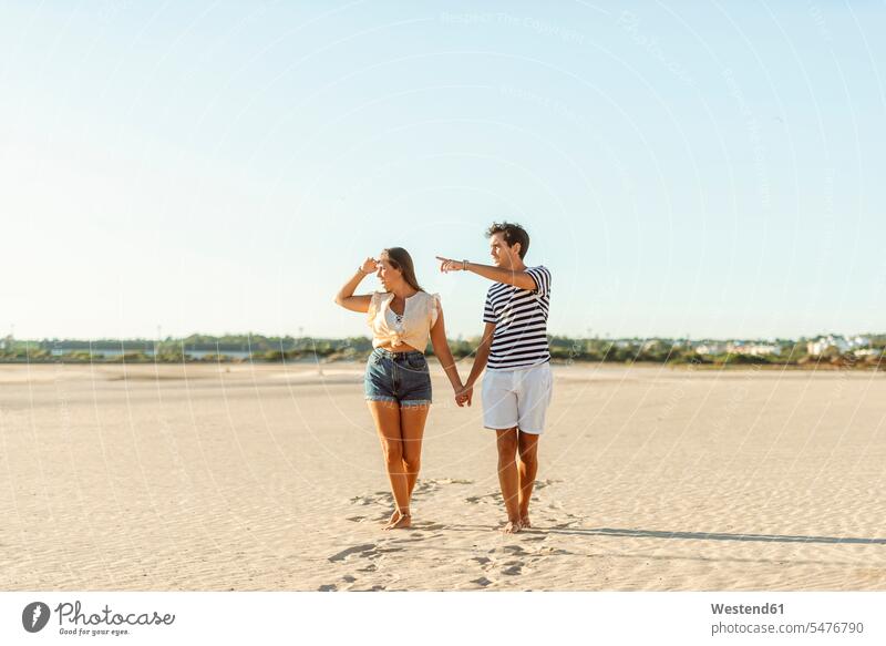 Young couple walking hand in hand on the beach beaches going twosomes partnership couples people persons human being humans human beings sandy beach