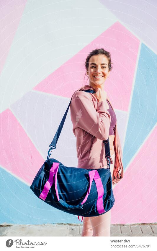 Sportive woman with sports bag looking at camera bags hold run smile delight enjoyment Pleasant pleasure happy content Contented Emotion pleased magenta Rosy