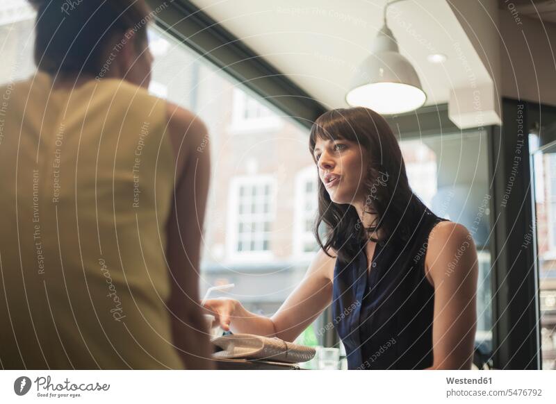 Businesswomen discussing while sitting in coffee shop color image colour image indoors indoor shot indoor shots interior interior view Interiors day