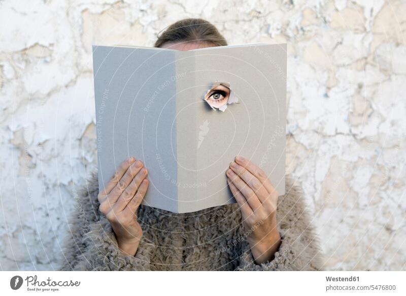Woman covering face with book, reading poetry, eye looking through cover Poetry wall walls books obscured face obscured faces face hidden eyes mysterious