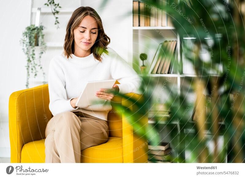 Businesswoman using digital tablet while sitting on sofa at office color image colour image indoors indoor shot indoor shots interior interior view Interiors