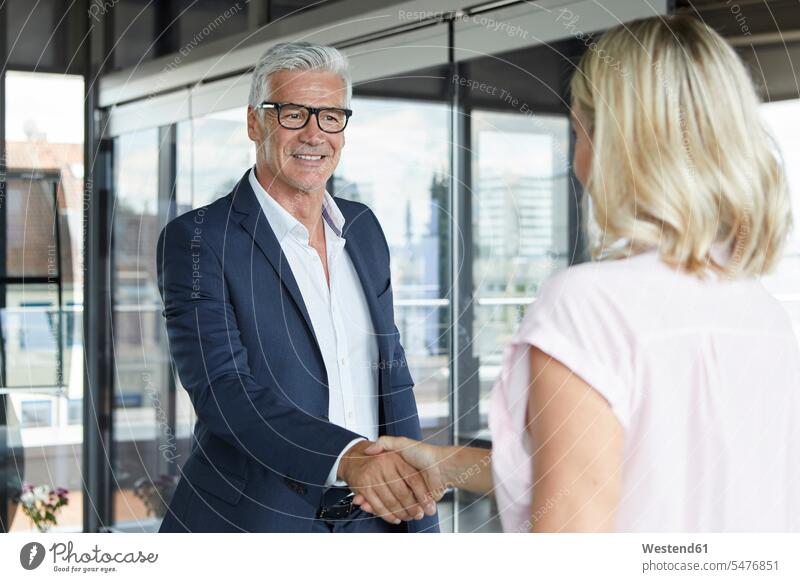 Businessman and woman shaking hands in office Meeting Meetings Business Meeting businesswoman businesswomen business woman business women Business man