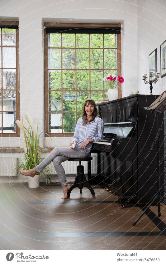 Woman sitting at piano, drinking coffee home at home woman females women Coffee Seated pianos Adults grown-ups grownups adult people persons human being humans
