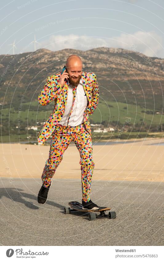 Smiling bald man on the phone wearing colourful suit while skateboarding on road streets roads Polka Dot Polka Dots Polka-Dot Polka-Dots baldy bald head smiling