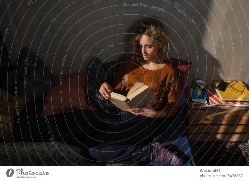 Blond student sitting on bed reading a book human human being human beings humans person persons caucasian appearance caucasian ethnicity european 1