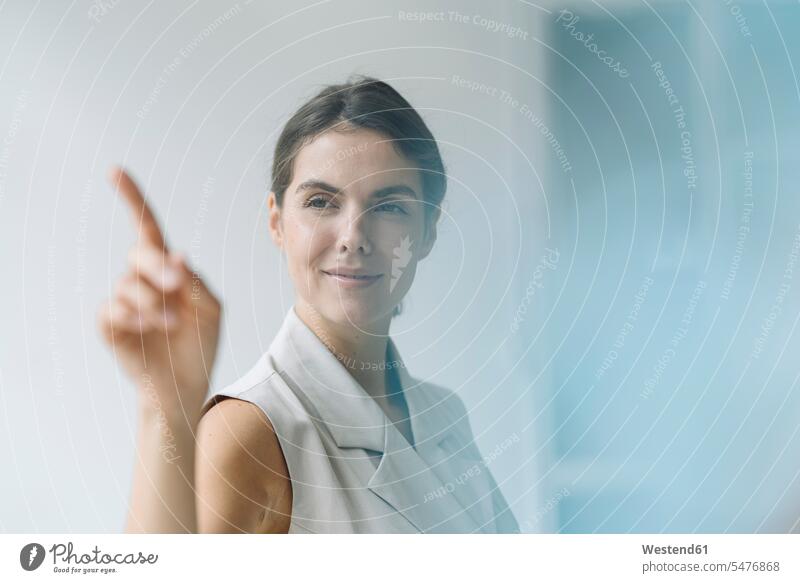 Smiling woman pointing on glass wall while standing at office color image colour image indoors indoor shot indoor shots interior interior view Interiors day