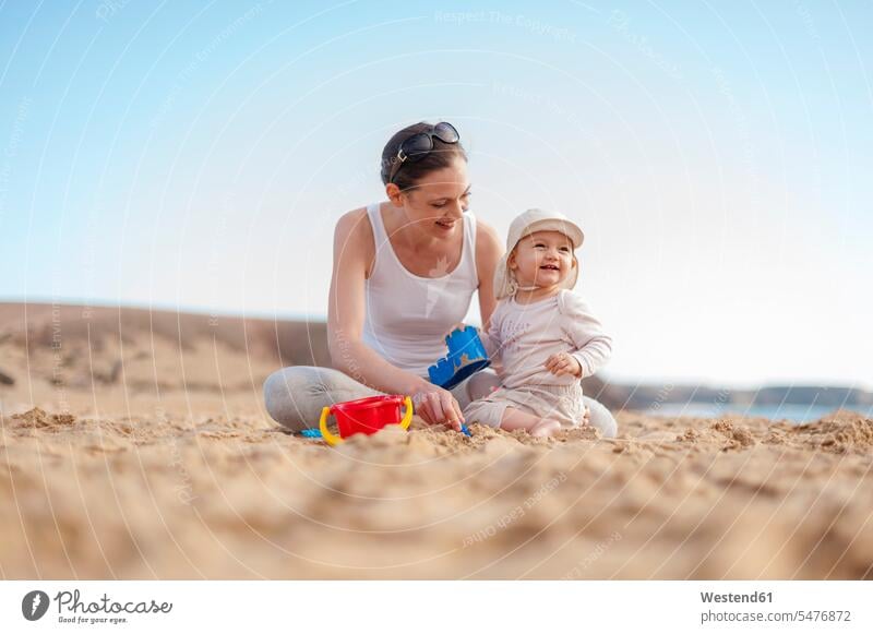 Mother playing with little daughter on the beach baby infants nurselings babies daughters mother mommy mothers ma mummy mama beaches people persons human being