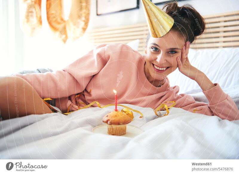 Happy young woman with cupcake during birthday bed beds muffin muffins alone solitary solo happiness happy females women Birthday Birthday Celebration Birthdays