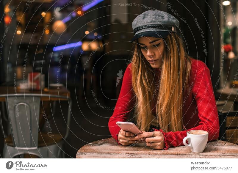 Portrait of young woman text messaging on terrace of a coffee shop females women portrait portraits Cafe Shop SMS Text Message terraces Adults grown-ups