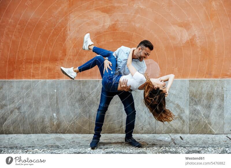 Carefree couple in love in front of a wall outdoors Love loving carefree twosomes partnership couples walls positive Emotion Feeling Feelings Sentiments