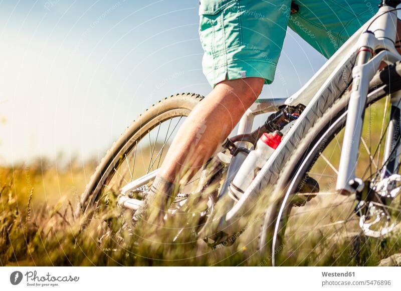 Close-up of woman riding mountainbike through grass bikes bicycles bike - bicycle Cycle Cycle - Vehicle apace quick rapidity rapidness speediness sports