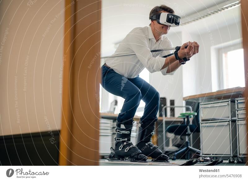 Businessman skiing in office, using VR glasses Business man Businessmen Business men Virtual Reality offices office room office rooms Virtual Reality Glasses