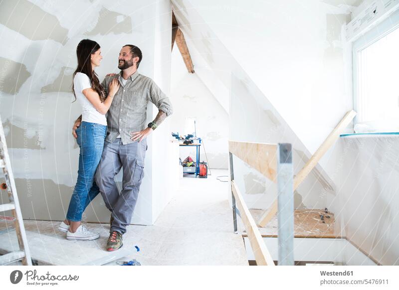 Smiling couple standing in attic to be renovated Attic Lofts Attics smiling smile renovation refurbish refurbishing Renovations redecorating renovating twosomes