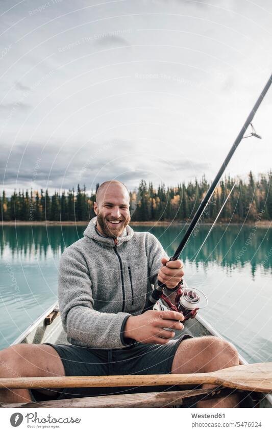 Canada, British Columbia, portrait of happy man fishing in canoe on Boya Lake happiness portraits angling men males lake lakes canoes boat boats vessel
