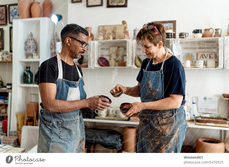 Coworkers holding potteries while standing in workshop color image colour image Spain indoors indoor shot indoor shots interior interior view Interiors working