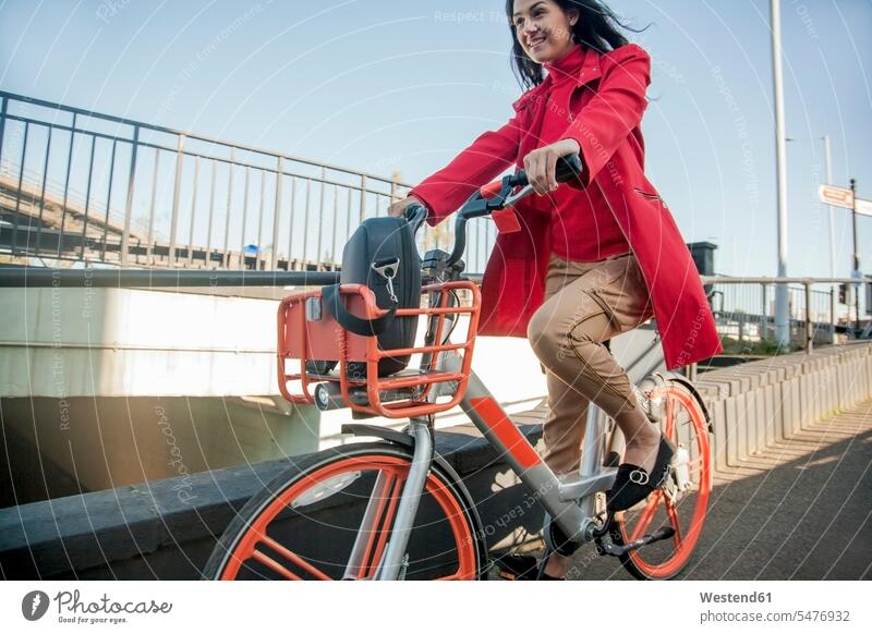 Young woman riding through the city on a rental bike business life business world business person businesspeople business woman business women businesswomen