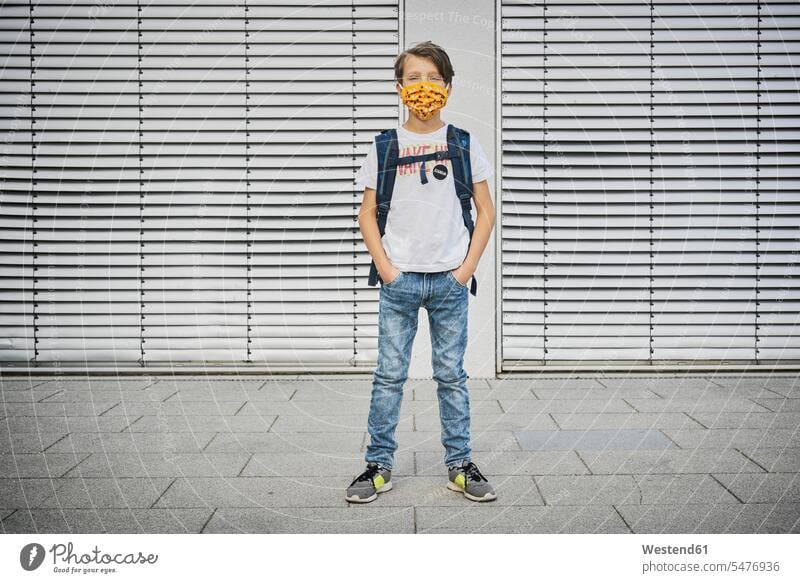 Boy with schoolbag wearing mask standing in front of building human human being human beings humans person persons caucasian appearance caucasian ethnicity