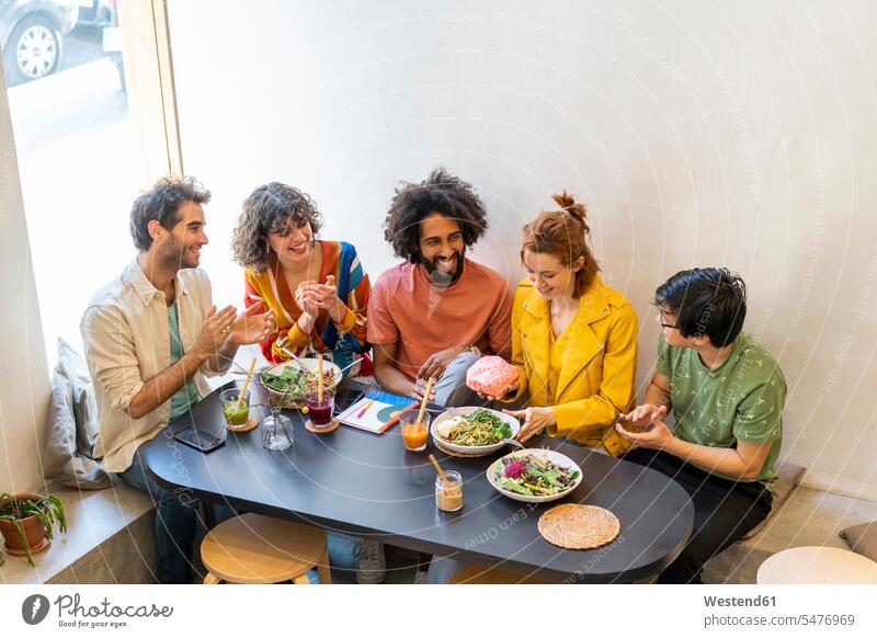 Group of friends having lunch in a restaurant Drinking Glass Drinking Glasses dish dishes Plates Tables applaud applauding applause clap hands Clapping smile