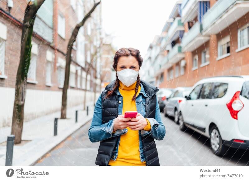 Woman wearing protective mask and using smartphone telecommunication phones telephone telephones cell phone cell phones Cellphone mobile mobile phones mobiles