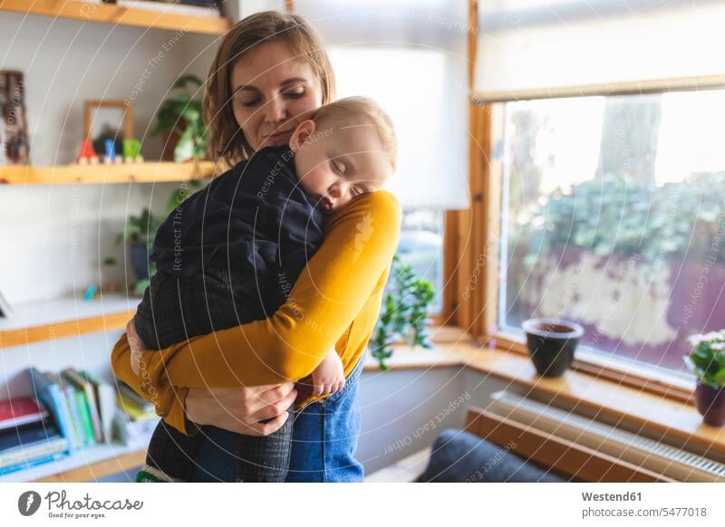 Mother holding her sleeping son on her shoulder windows relax relaxing cuddle snuggle snuggling asleep embrace Embracement hug hugging Secure Emotions Feeling