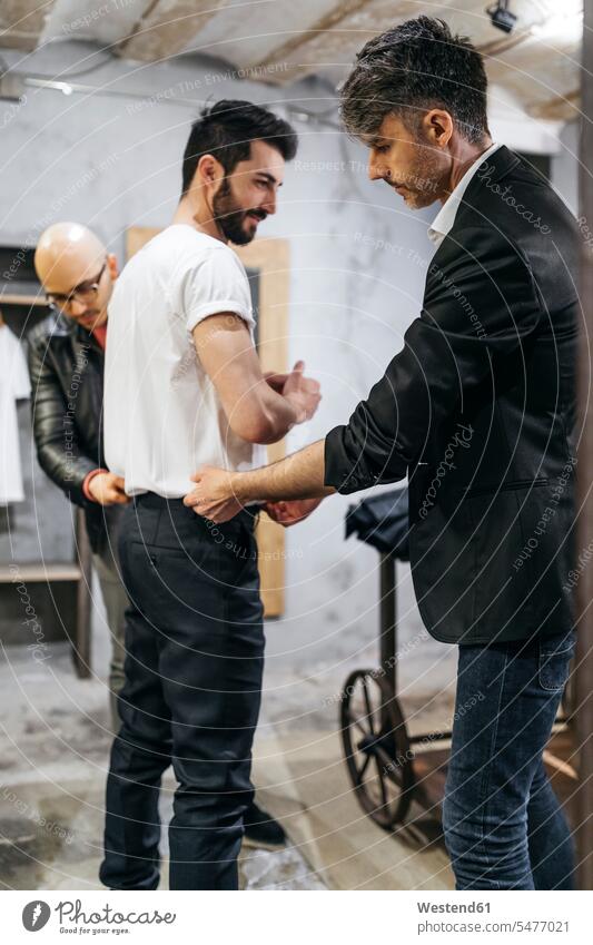 Two men working on new stylish look for handsome man in showroom customer clientele clients customers men's fashion males shop modern contemporary people