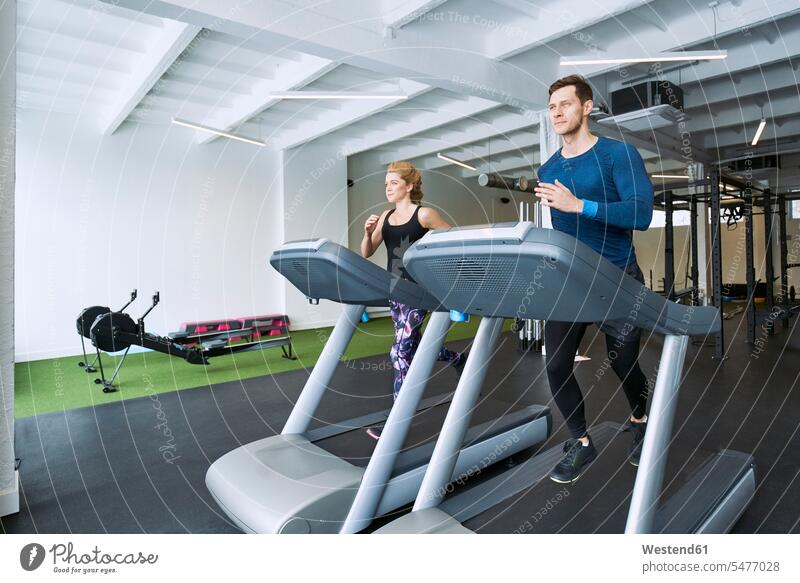 Man and woman running on treadmill at gym gyms Health Club men males females women Treadmills running machine fitness sport sports Adults grown-ups grownups