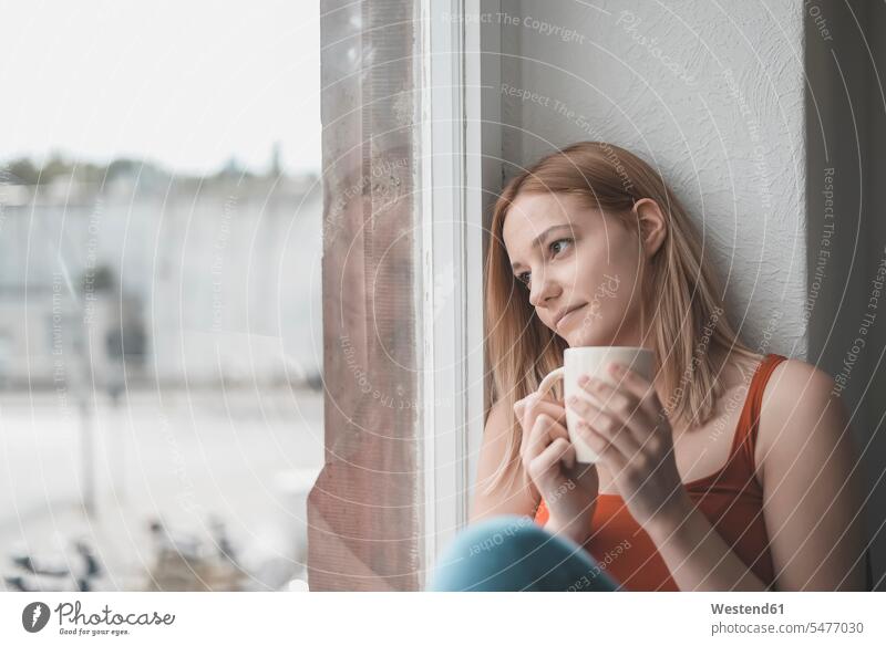 Portrait of pensive young woman with cup of coffee looking out of window human human being human beings humans person persons celibate celibates singles