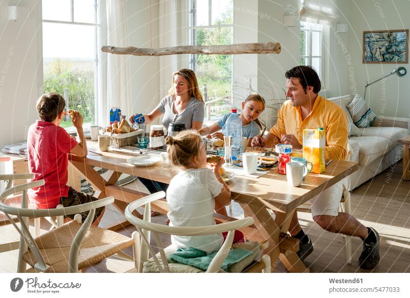 Family having breakfast at dining table windows chairs Seated sit in the morning seasons summer time summertime summery enjoy enjoyment indulgence indulging
