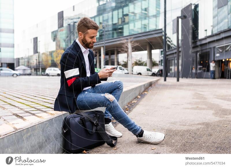 Stylish businessman sitting in the city using cell phone Businessman Business man Businessmen Business men town cities towns males style stylish Seated