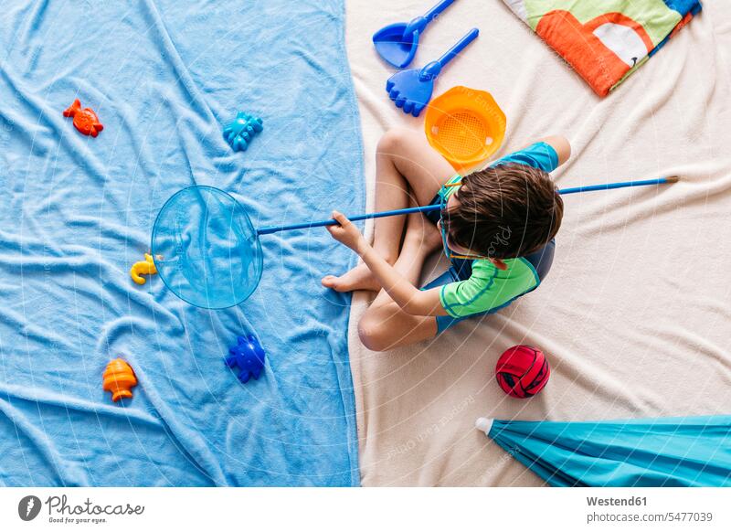 Studio shot of boy fishing with fishing net in water sitting at beach Fishes Blankets towels Brolly umbrellas sunshades balls toys Eye Glasses Eyeglasses specs