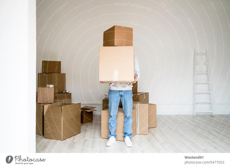 Young man carrying stack of boxes while standing in new apartment color image colour image indoors indoor shot indoor shots interior interior view Interiors day