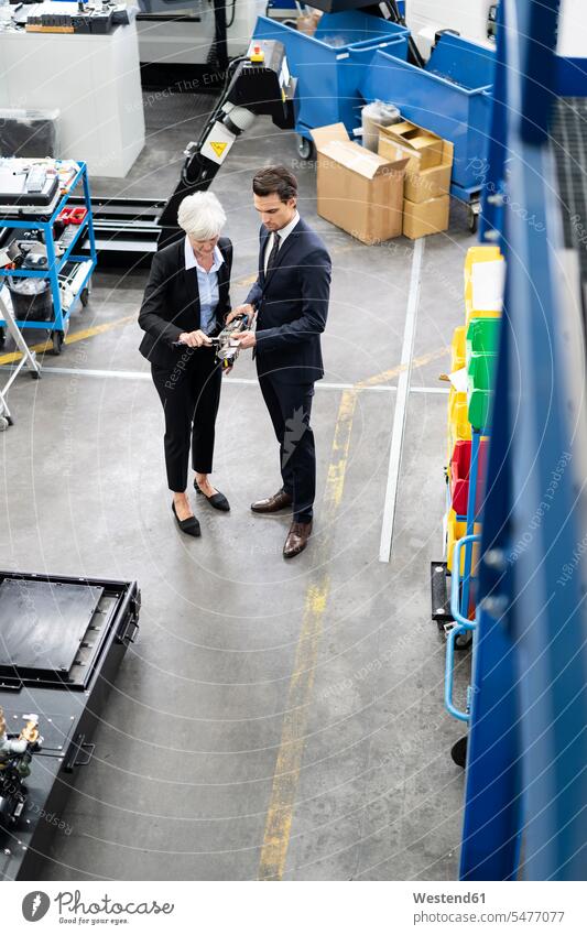 Businessman and senior businesswoman examining workpiece in a factory checking examine Business man Businessmen Business men talking speaking businesswomen