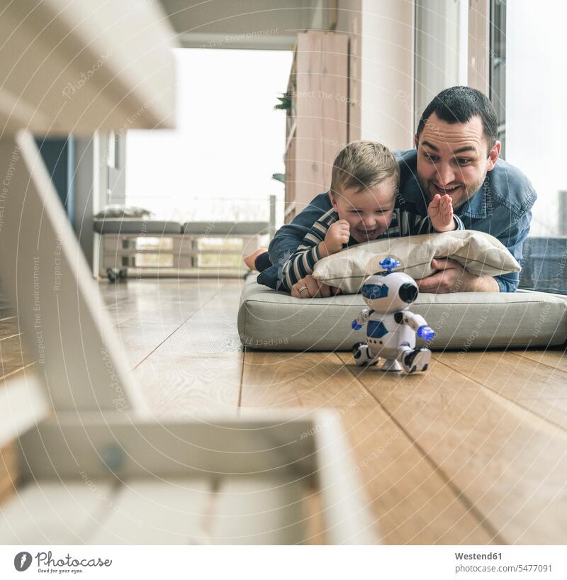 Excited father and son lying on a mattress at home watching a toy robot laying down lie lying down excitement Exciting pa fathers daddy dads papa Mattress