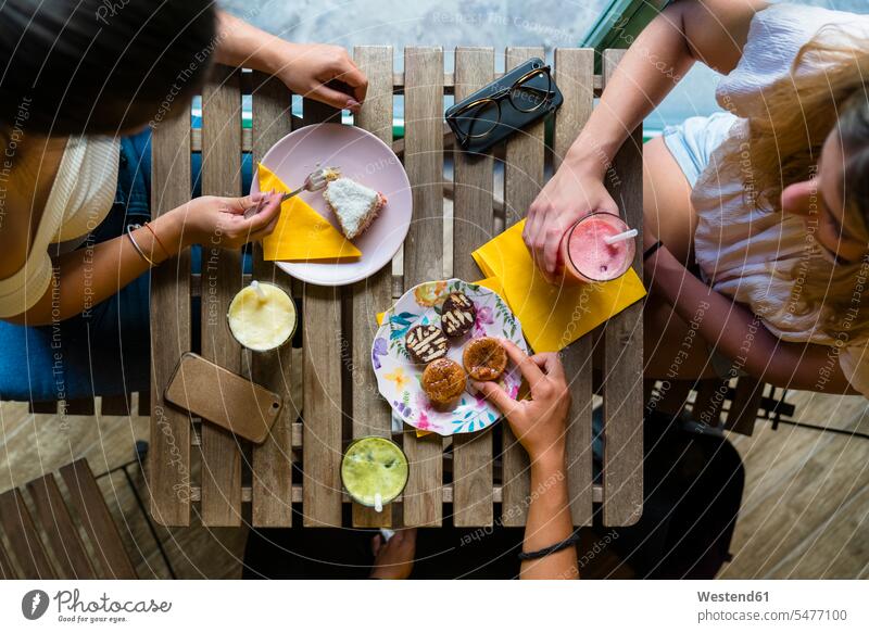 Top view of three young women sitting at wooden table with smoothies and biscuits human human being human beings humans person persons caucasian appearance