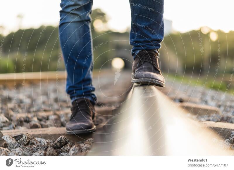 Young man standing on railroad track rails men males steadfast shoe shoes transportation Adults grown-ups grownups adult people persons human being humans