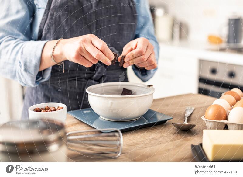 Woman weighing chocolate on kitchen scale while standing by kitchen island at home color image colour image indoors indoor shot indoor shots interior