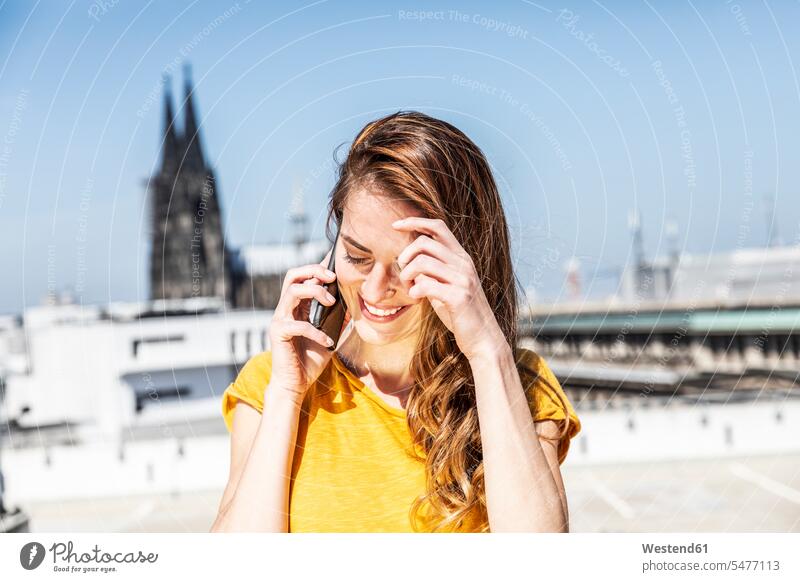 Germany, Cologne, smiling woman on the phone females women call telephoning On The Telephone calling smile Adults grown-ups grownups adult people persons