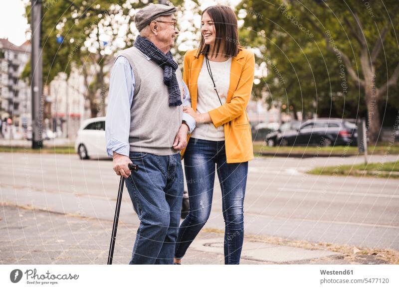 Adult granddaughter assisting her grandfather strolling with walking stick human human being human beings humans person persons caucasian appearance
