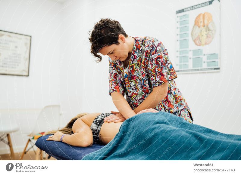 Osteopath therapist giving back massage to sportswoman in medical room color image colour image indoors indoor shot indoor shots interior interior view