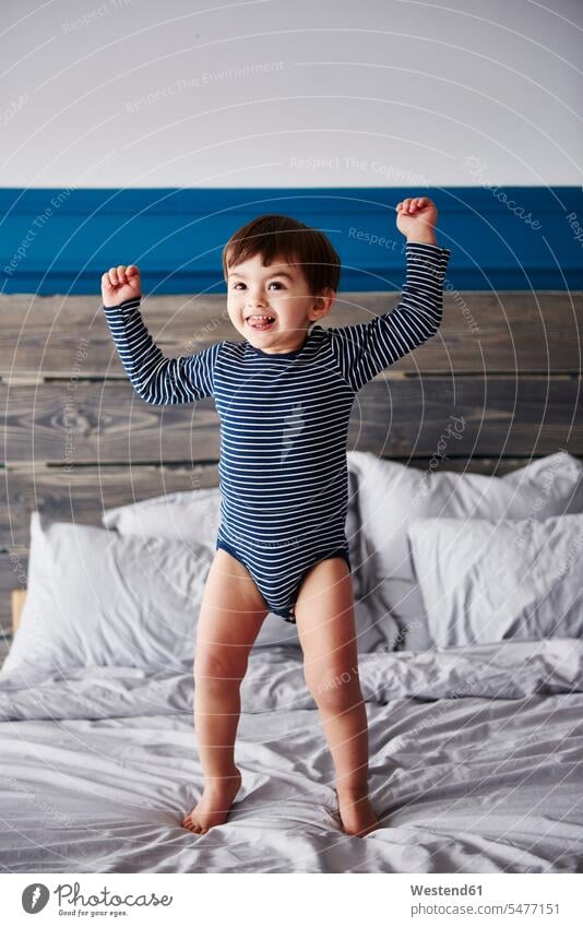 Portrait of happy toddler jumping on bed happiness baby boys male beds Leaping portrait portraits babies infants people persons human being humans human beings