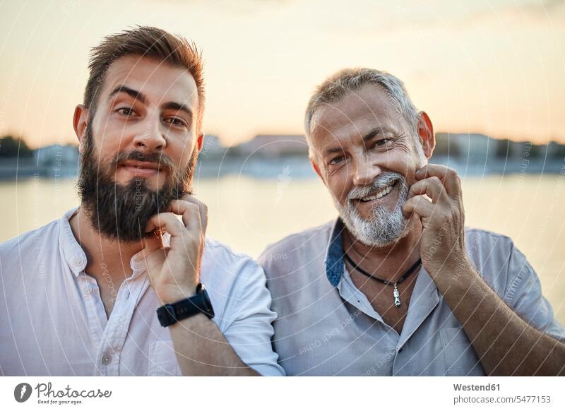 Portrait of smiling father and adult son scratching their beards generation shirts smile in the evening summer time summertime summery relax relaxing relaxation