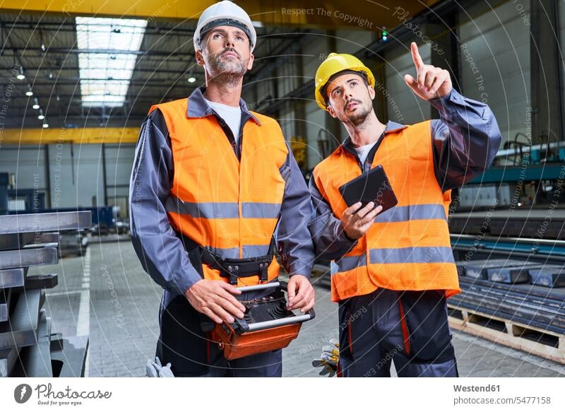 Two men in factory talking and operating machinery with remote console operate man males remote control Console speaking Adults grown-ups grownups adult people