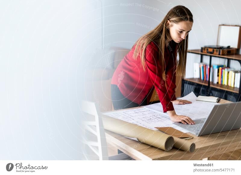Woman in office working on plan and laptop on table human human being human beings humans person persons caucasian appearance caucasian ethnicity european adult