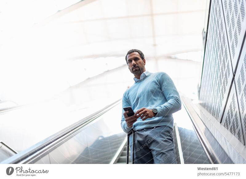 Businessman with smartphone on escalator Business man Businessmen Business men portrait portraits on the phone call telephoning On The Telephone calling