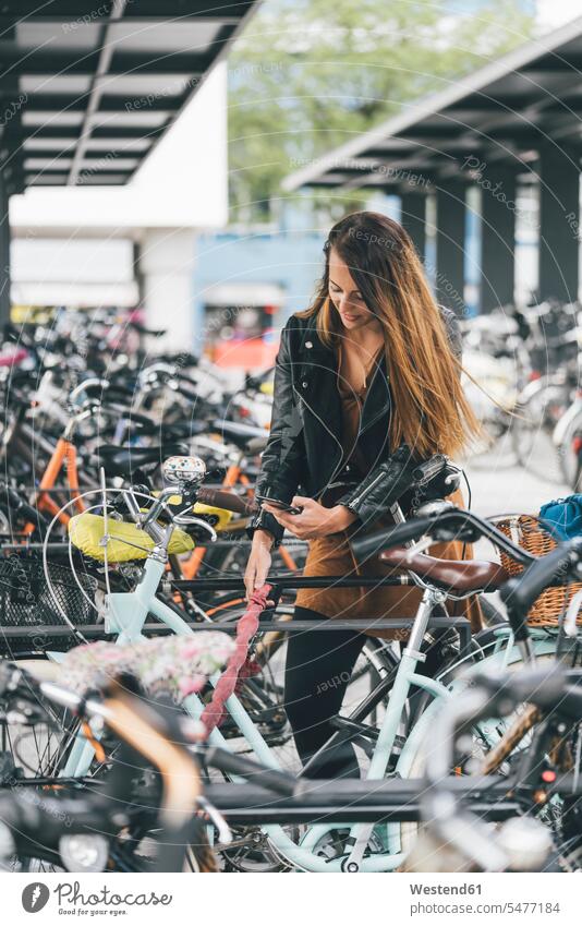 Young woman with bicycle using cell phone in the city females women town cities towns mobile phone mobiles mobile phones Cellphone cell phones bikes bicycles